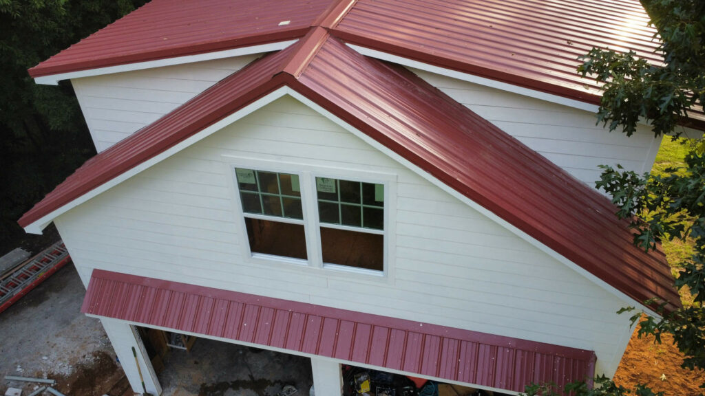 New red standing-seam metal roof on a home under construction