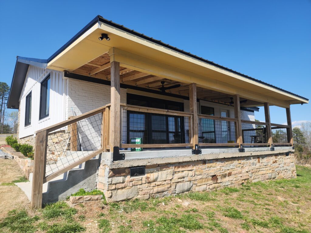Newly built back porch on a house with stairs and railing