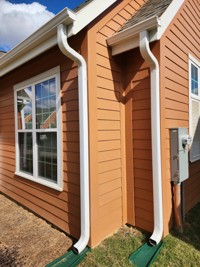 Close-up of two white downspouts with splash blocks