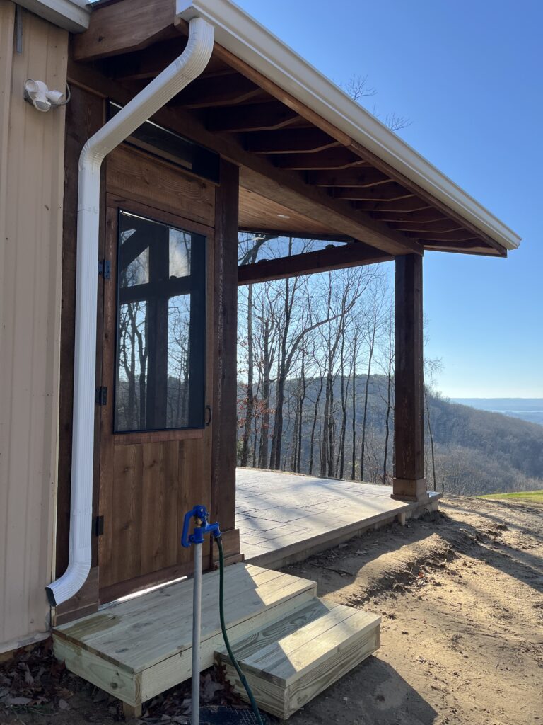 New porch patio area behind a house with siding and a rainspout